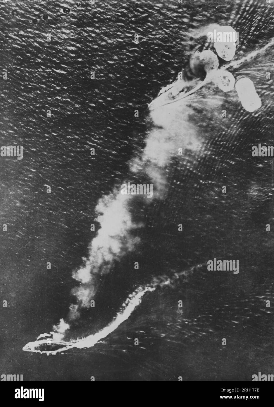 Campaña Malaya, diciembre 1941 – febrero 1942. Una foto aérea tomada al norte de Malaya, sobre el Mar de China Meridional, muestra al acorazado HMS Prince of Wales (arriba) y al crucero de batalla HMS Repulse, bajo ataque de un avión de la Armada Imperial Japonesa, el 10 de diciembre de 1941. Los dos barcos sucumbirían a los ataques japoneses más tarde en el día, lo que resultó en una pérdida devastadora de activos navales aliados en el Pacífico. Foto de stock