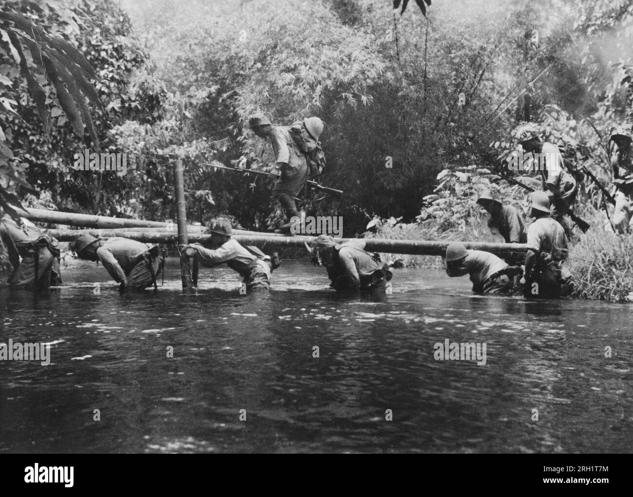 Campaña Malaya, diciembre 1941 – febrero 1942. Durante su avance de cincuenta y cinco días que abarca casi mil kilómetros desde Songkhla a Johor Bahru, ingenieros del Ejército Imperial Japonés levantaron un puente improvisado a través de uno de los muchos arroyos de la selva para que su infantería pase, alrededor de enero de 1942. Foto de stock