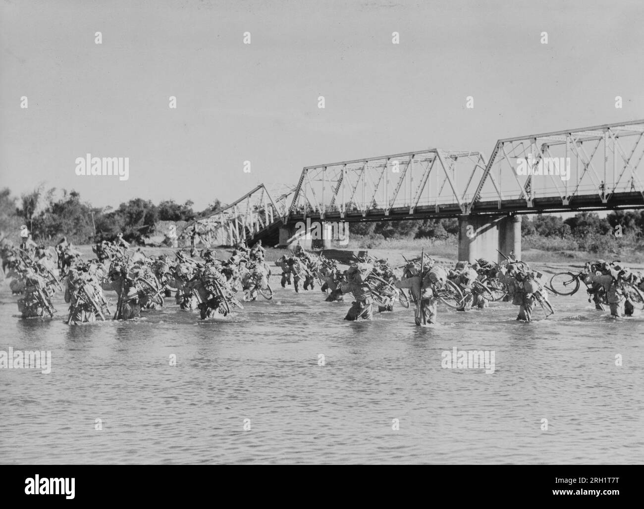 Campaña Malaya, diciembre 1941 – febrero 1942. Sin el lujo de perder un tiempo precioso esperando a que sus ingenieros reparen otro puente caído, Ginrin Butai (Cuerpo Ciclista de Plata) del Ejército Imperial Japonés cruzó un río mientras continuaban en su viaje inquebrantable hacia Singapur, alrededor de febrero de 1942. Foto de stock