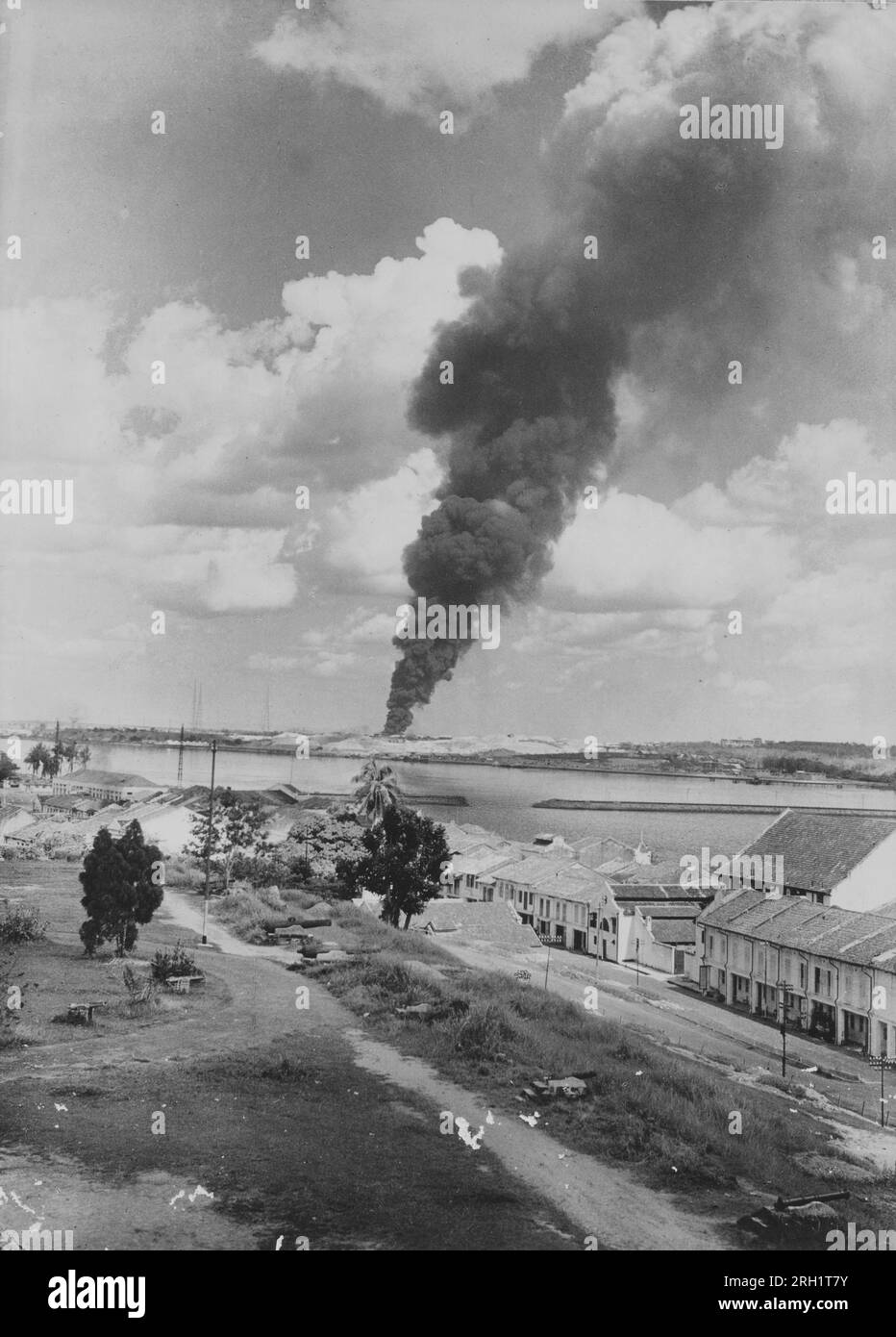 Campaña Malaya, diciembre 1941 – febrero 1942. Una foto tomada por el Ejército Imperial Japonés invasor muestra un gran agujero soplado en la calzada que una vez conectó Singapur con Johor como humo de un bombardeo japonés cerca de Seletar se inunda en la distancia, alrededor de febrero de 1942. El 31 de enero, cuando los japoneses se acercaban, las tropas británicas en Johor se habían retirado de sus posiciones en Singapur y detonaron la calzada detrás de ellos en un intento de cortar el avance japonés en Singapur. Foto de stock