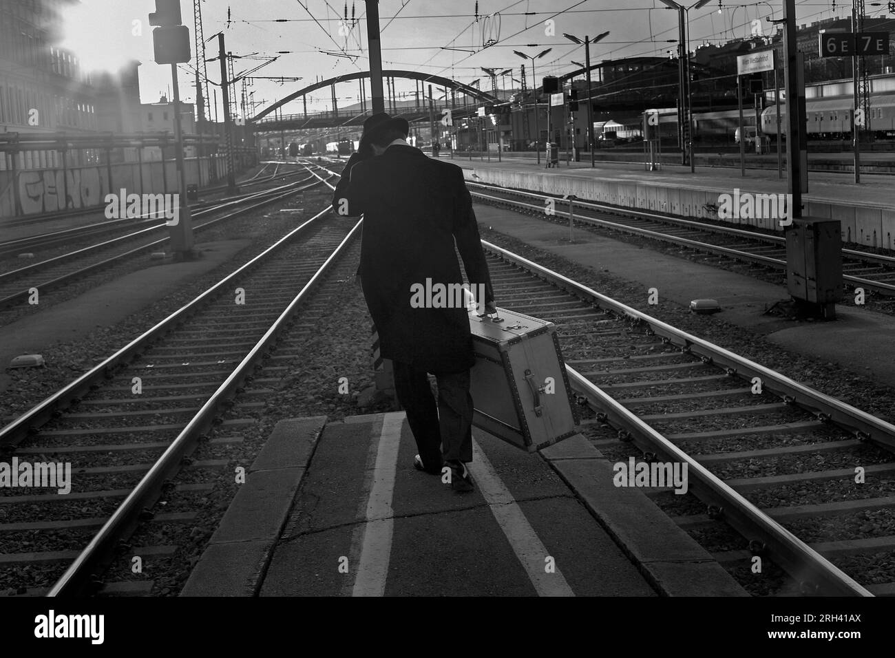 El hombre con la maleta camina al extremo lejano de los estantes de la estación de la plataforma en horas tempranas de la mañana Foto de stock