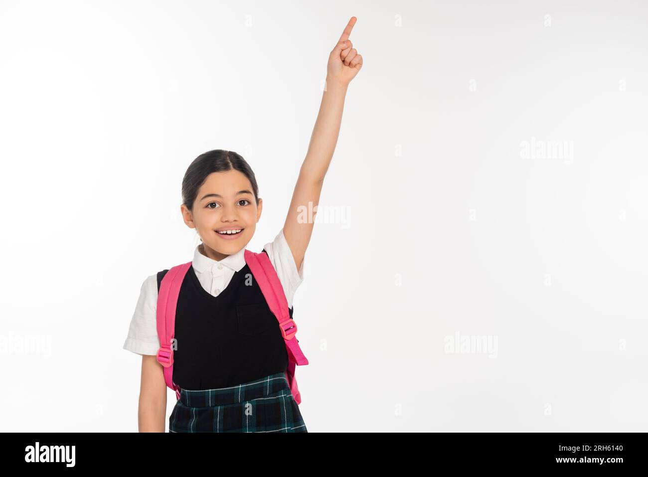 chica feliz en uniforme escolar mostrando algo, señalando con el dedo aislado en blanco, estudiante Foto de stock