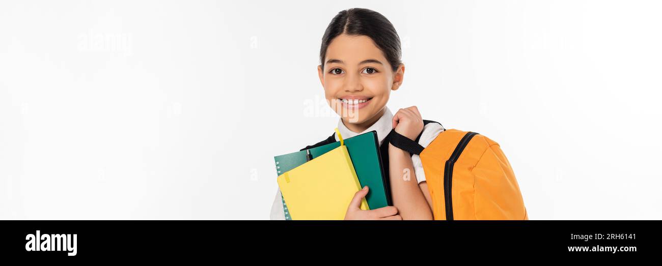 colegiala feliz de pie con cuadernos y mochila en manos, nuevo concepto de año escolar, bandera Foto de stock