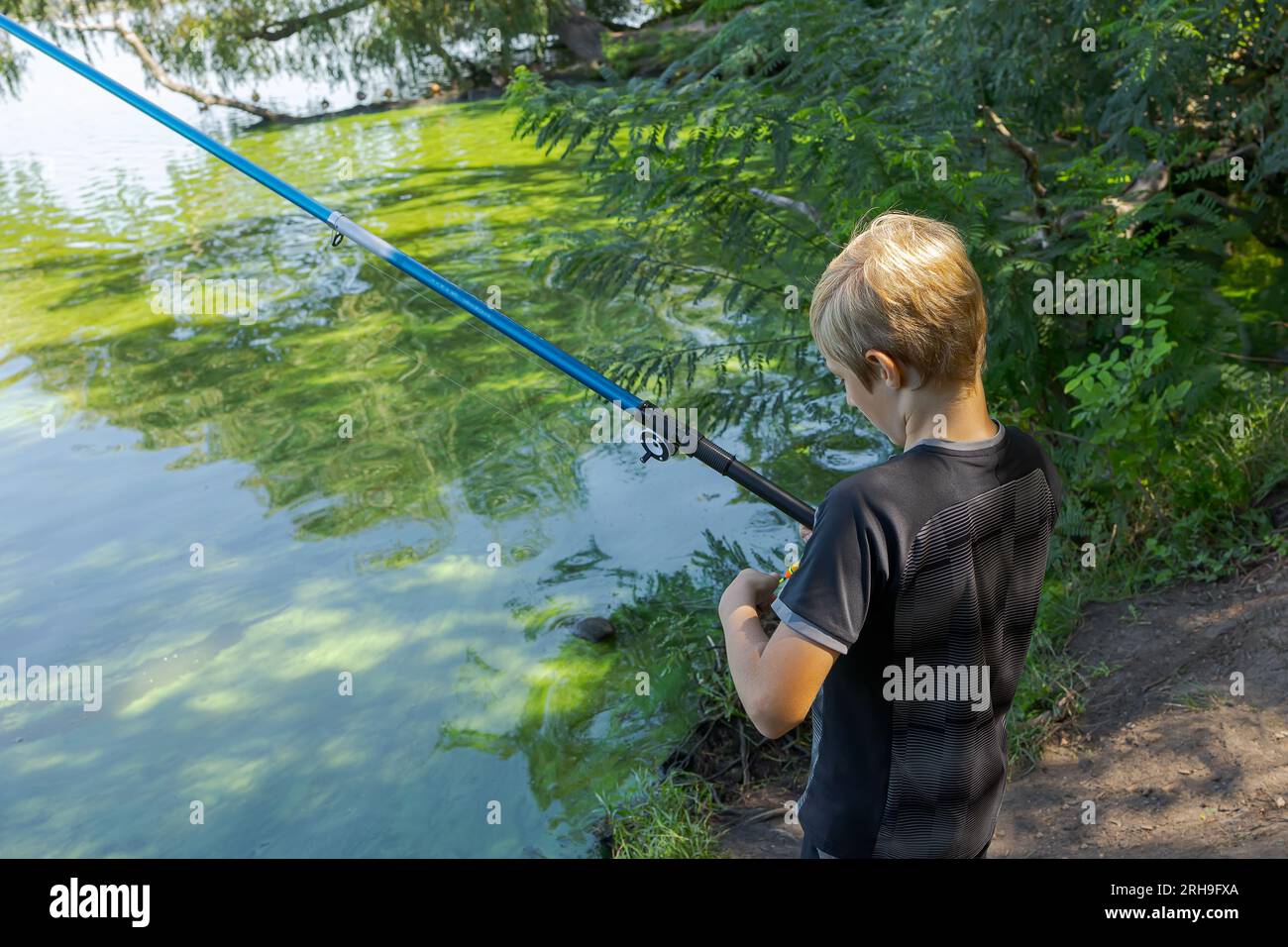 Un niño lanza una caña de pescar para atrapar peces. Pesca deportiva en el  río en verano Fotografía de stock - Alamy