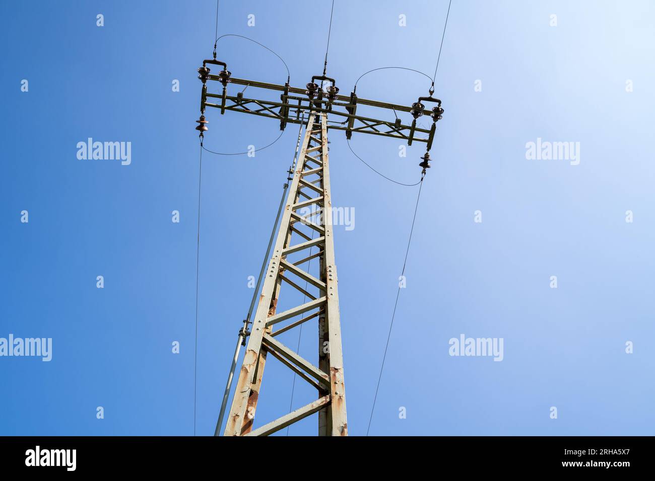 Pilón de electricidad con líneas de alta tensión en el cielo azul Foto de stock