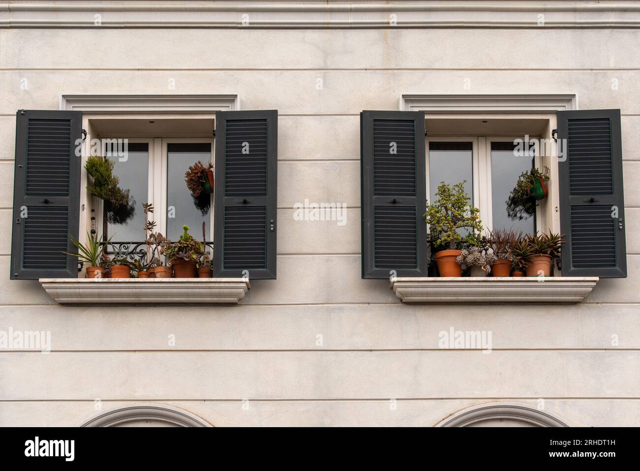 Fachada de un elegante palacio con un par de ventanas y plantas en macetas en los alféizares de las ventanas, Liguria, Italia Foto de stock