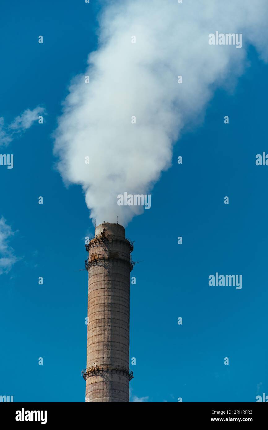 Tubo con humo denso sobre fondo de cielo azul Foto de stock