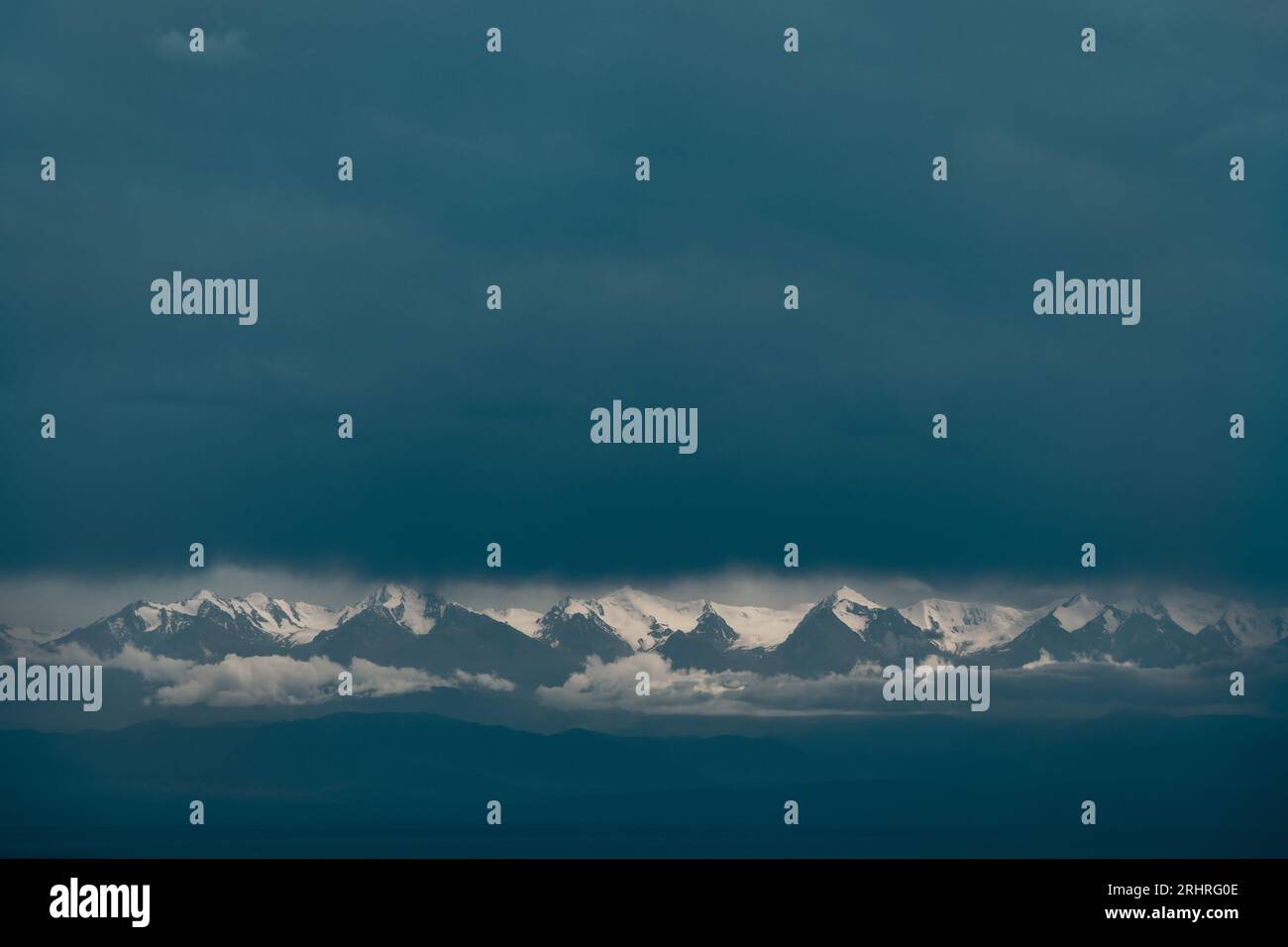 Pintoresco paisaje dramático de cimas de montañas cubiertas de nieve entre nubes y niebla Foto de stock