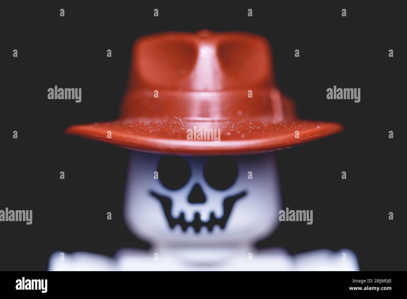 Un pequeño esqueleto de plástico blanco con un sombrero negro y una camisa de rayas rojas y blancas Foto de stock