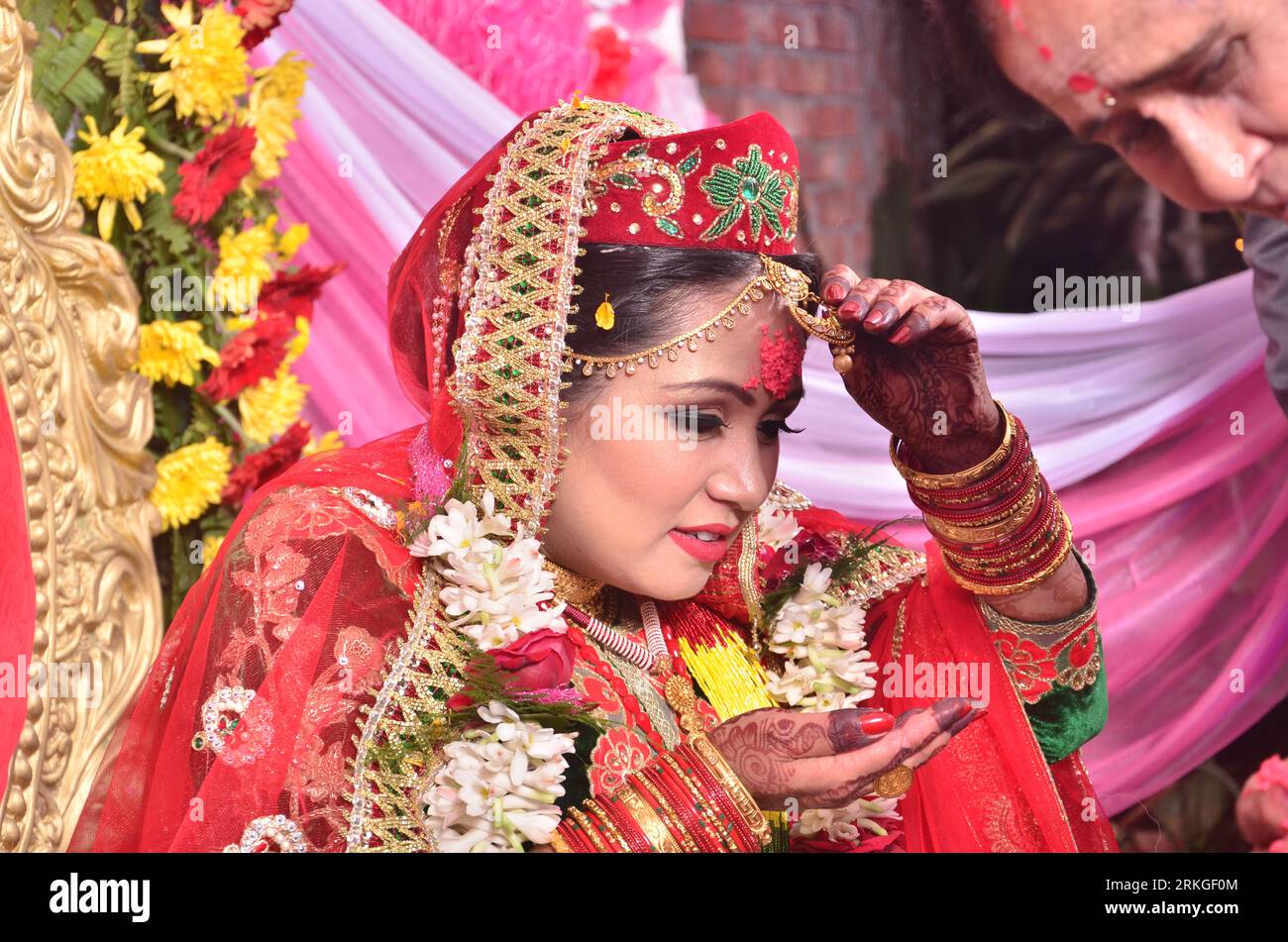 Una novia nepalí sonriente feliz iwearing un sari rojo y joyas de oro. Foto de stock