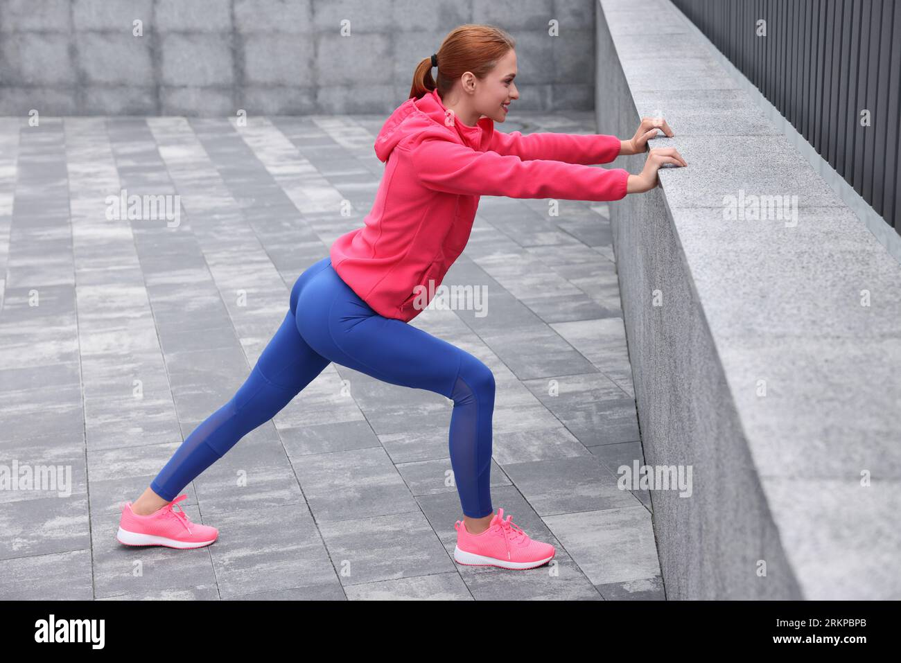 Hermosa mujer en ropa de gimnasio haciendo ejercicios en la calle Foto de stock