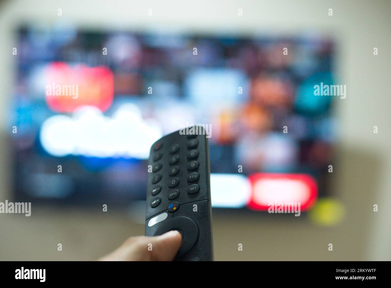 Mano con control remoto de TV, cambiando series de TV de la plataforma de servicio de streaming. La nueva forma de disfrutar del entretenimiento en casa. Foto de stock