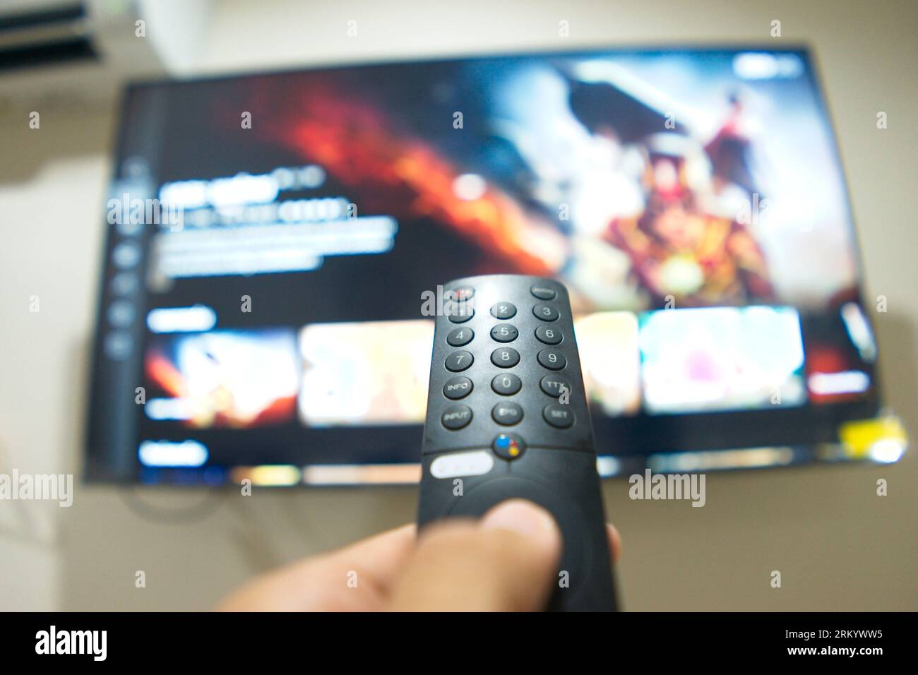 Mano con control remoto de TV, cambiando series de TV de la plataforma de servicio de streaming. La nueva forma de disfrutar del entretenimiento en casa. Foto de stock