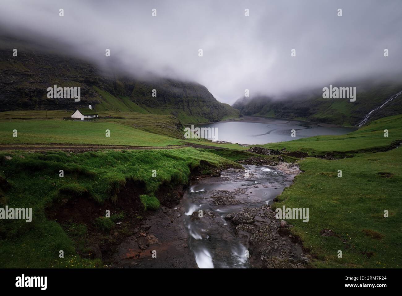 Islas Feroe - Casas de techo de hierba en el pequeño pueblo Saksun, atmósfera de nubes oscuras Foto de stock