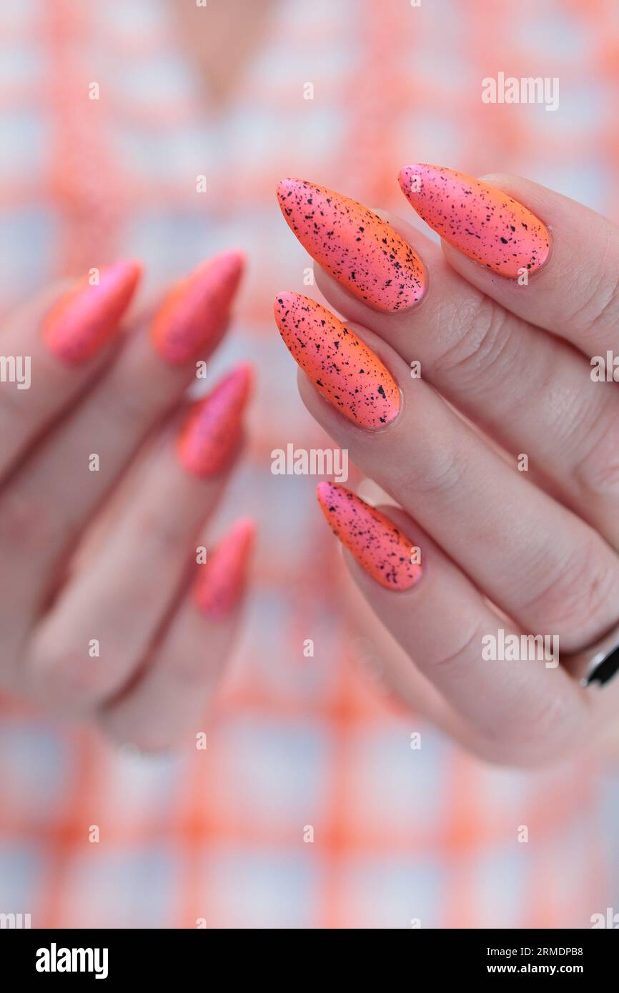 Hermosa mano femenina con uñas largas y un esmalte de uñas naranja  brillante Fotografía de stock - Alamy