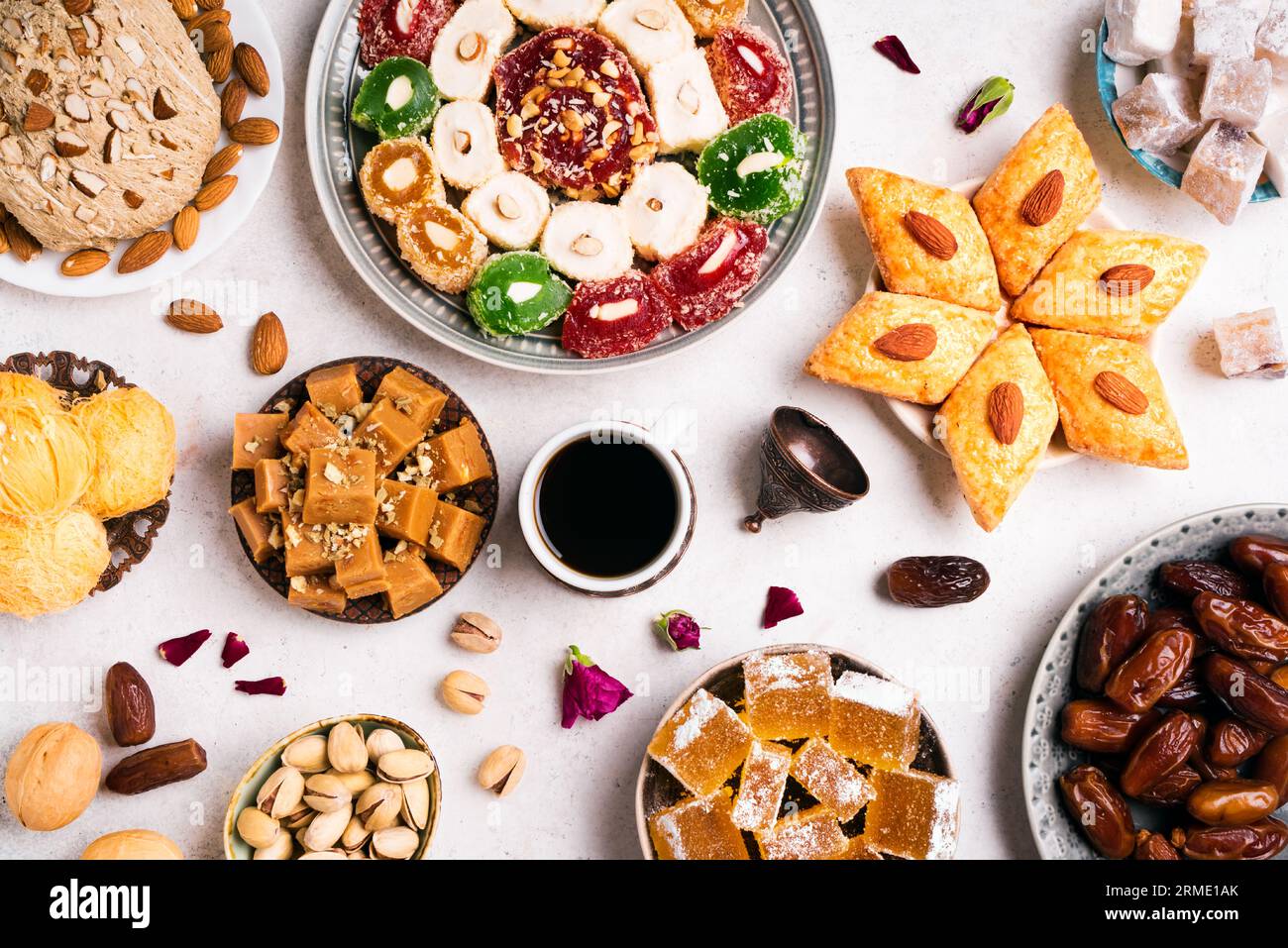 Dulces de Oriente Medio, delicias turcas y café negro sobre fondo blanco. Surtido de postres árabes, rahat lokum, halva, sherber, pismaniye con nuez Foto de stock