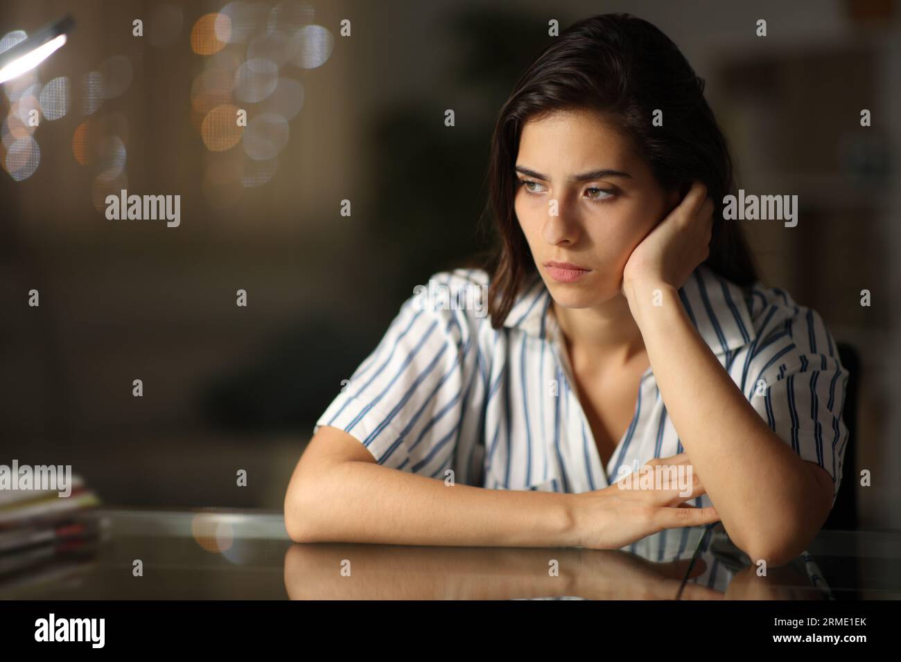 Mujer pensativa triste mirando lejos sola en casa en la noche Foto de stock