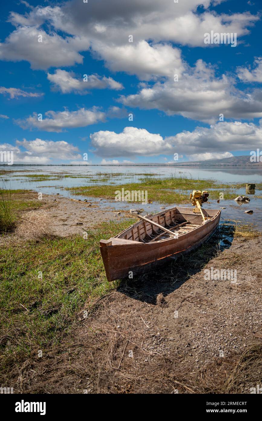 Barco abandonado en tierra agrietada en el lecho del lago se secó debido al calentamiento global y la sequía Foto de stock