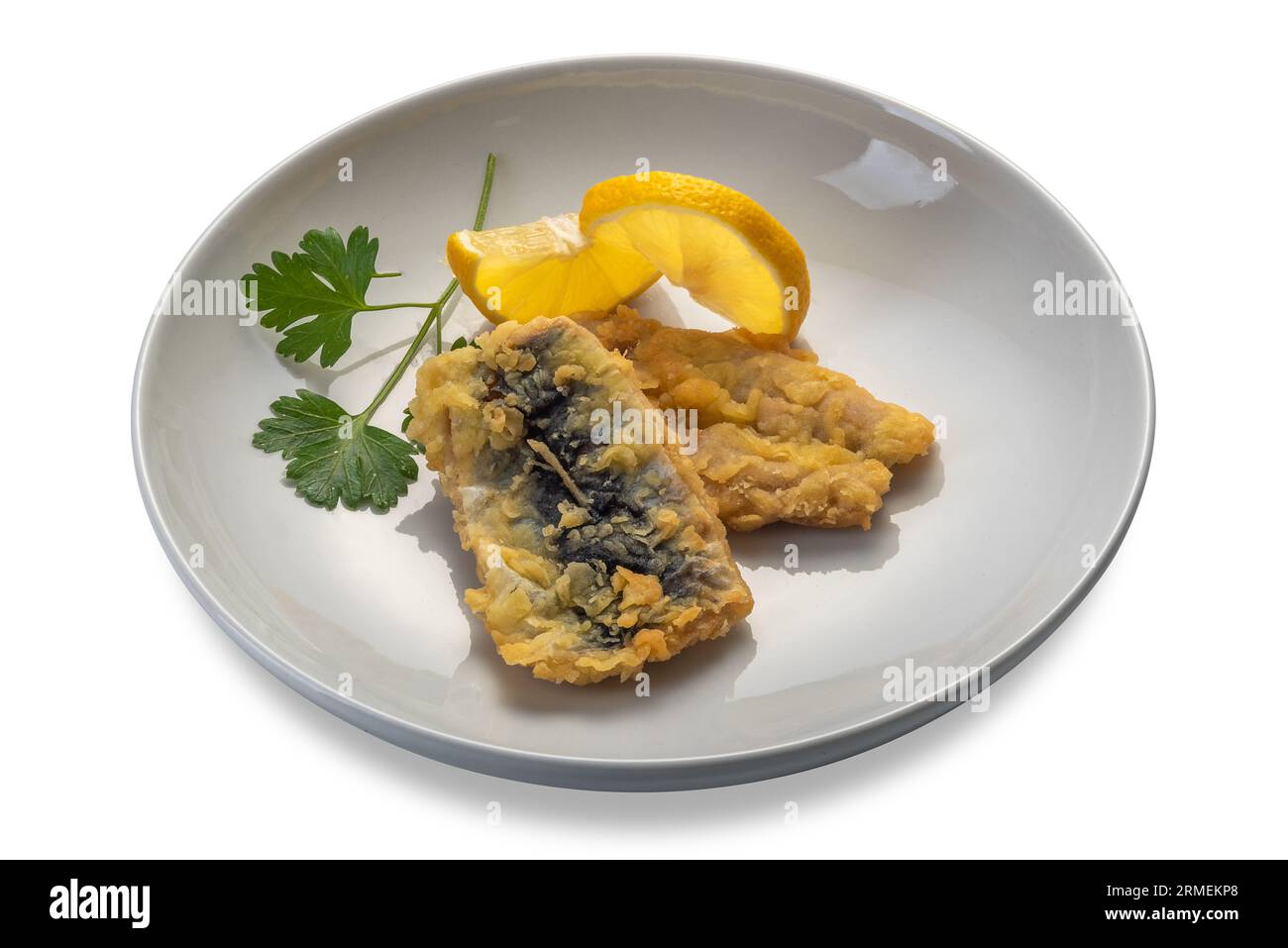 Pescado de sardina azul rebozado con hojas de perejil y rodajas de limón en un plato aislado en blanco con ruta de recorte incluida Foto de stock