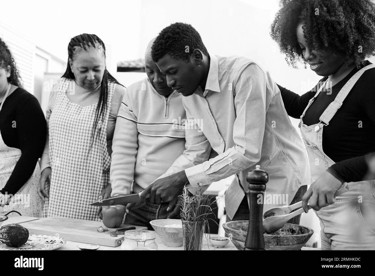 Cocina al aire libre: Familia africana que cocina comida vegetariana en el patio de casa - Padre, madre, hija, hermano que hace la cena de la comida sana - Enfoque suave en r Foto de stock