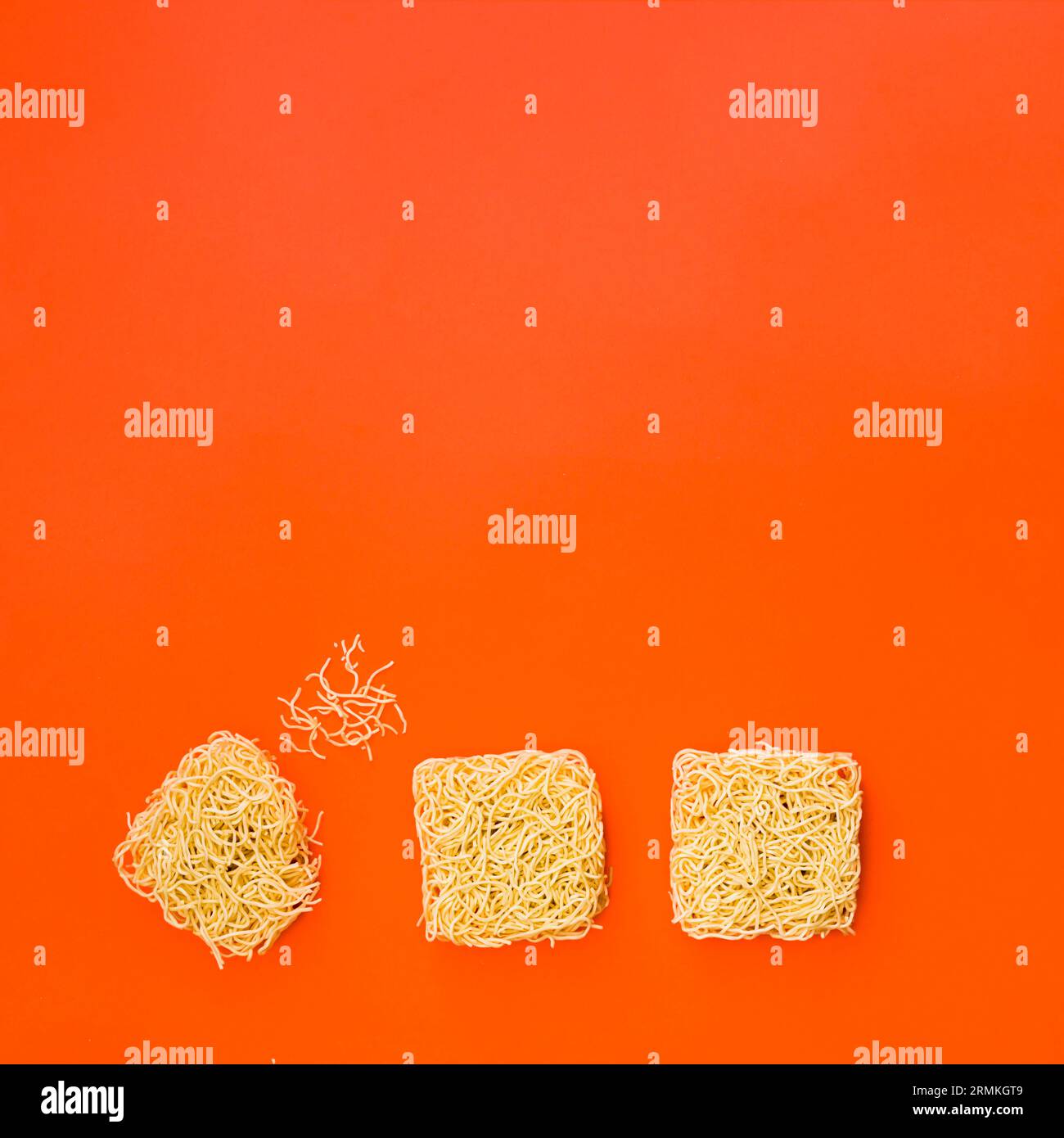 Bloques de fideos instantáneos dispuestos superficie naranja brillante Foto de stock
