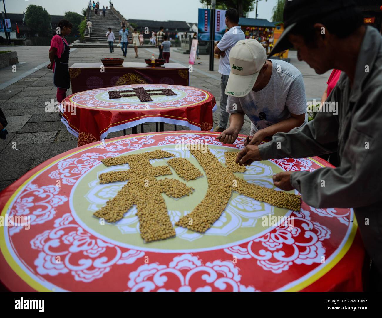 (140904) -- HANGZHOU, 4 de septiembre de 2014 -- Los residentes locales hacen caracteres chinos con frijoles de soja y frijoles rojos en un banquete de calle para celebrar el próximo Festival del Medio Otoño en la ciudad de Tangxi de Hangzhou, provincia de Zhejiang del este de China, 4 de septiembre de 2014. El Festival del Medio Otoño, que se celebra el 8 de septiembre de este año, es un festival tradicional chino para reuniones familiares. (mp) CHINA-ZHEJANG-TANGXI CIUDAD-MEDIOS DE OTOÑO FESTIVAL-CELEBRACIÓN (CN) XuxYu PUBLICATIONxNOTxINxCHN Hangzhou Sept 4 2014 Los residentes locales hacen personajes chinos por soja y frijoles rojos en un banquete de calle larga para celebrar el Comi Foto de stock
