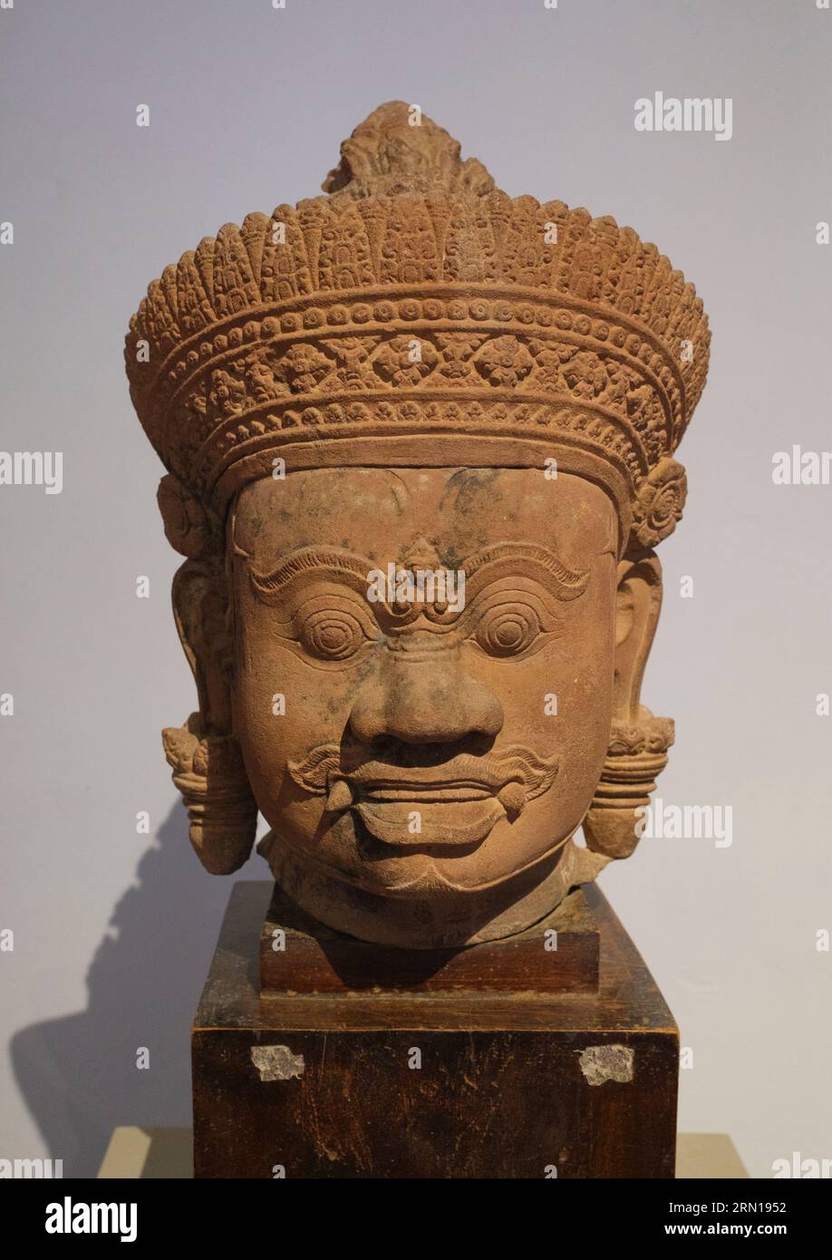 Camboya: Una cabeza de piedra arenisca del siglo X de una Yaksha (deidad guardiana) originaria del templo Banteay Srei cerca de Siem Reap, ahora en el Museo Nacional de Camboya, Phnom Penh. El Museo Nacional, ubicado en un pabellón rojo construido en 1918, alberga una colección de arte jemer que incluye algunas de las mejores piezas existentes. Las exposiciones incluyen una estatua de Vishnu del siglo VI, una estatua de Shiva del siglo IX y la famosa cabeza esculpida de Jayavarman VII en pose meditativa. Particularmente impresionante es un busto dañado de un Vishnu reclinado, una vez parte de una estatua de bronce masiva encontrada en el oeste de Mebon. Foto de stock