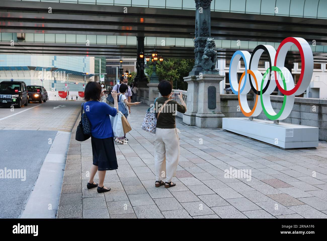 TOKIO, JAPÓN - 28 de julio de 2021: La gente toma fotos de un monumento del Anillo Olímpico a última hora de la tarde en el puente Nihonbashi. Foto de stock