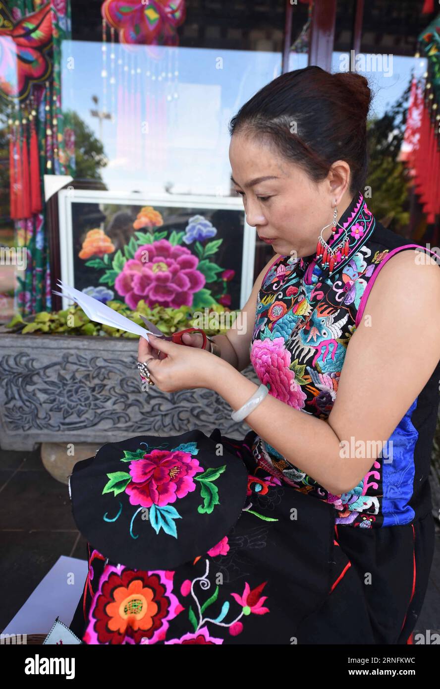 DAYAO, 14 de agosto de 2016 -- Luo Jun hace una muestra de producto de bordado en el taller en la Prefectura Autónoma de Chuxiong Yi, provincia de Yunnan, suroeste de China, 14 de agosto de 2016. Luo Jun, empresaria del grupo étnico Yi, estableció una cooperativa en 2011 para producir bordados con estilo étnico Yi único, como vestidos, bolsos, anillos de oreja y etc. En los primeros ocho meses de este año, las ventas de su cooperativa alcanzaron 17 millones de yuanes (alrededor de 2,56 millones de dólares). (wsw) CHINA-YUNNAN-YI ETNICO-BORDADO (CN) YangxZongyou PUBLICATIONxNOTxINxCHN Dayao Aug 14 2016 Luo jun hace una muestra de E Foto de stock