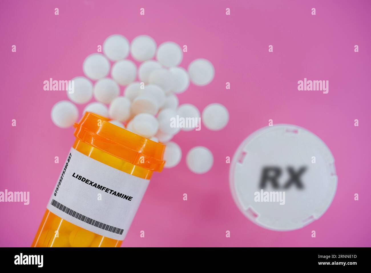 Lisdexamfetamine Rx píldoras de medicina en vial pláctico con tabletas. Pastillas derramando desde el contenedor amarillo sobre fondo rosa. Foto de stock