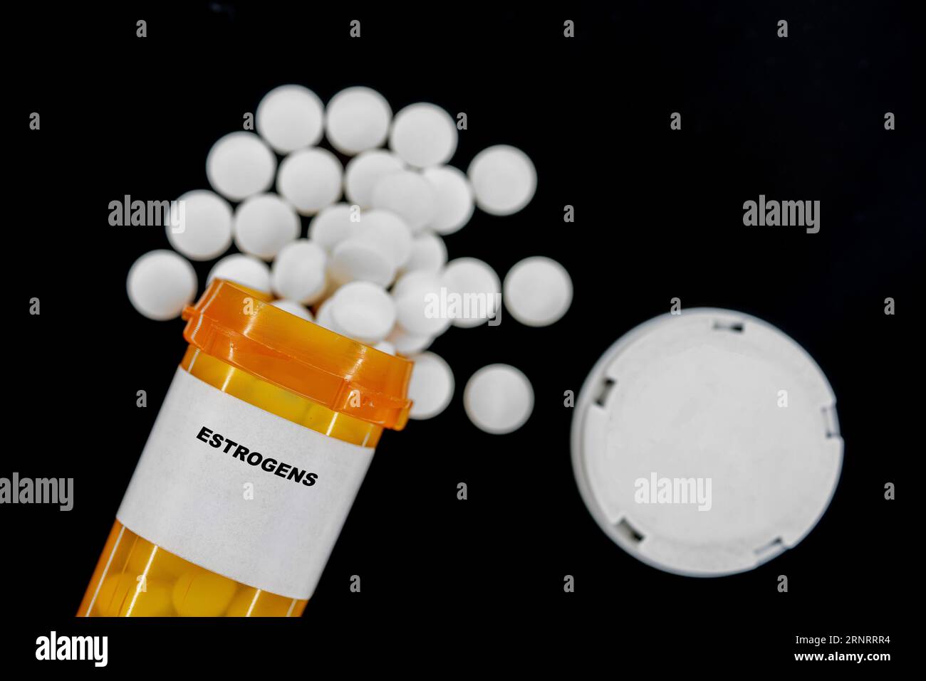 Estrogens Rx píldoras médicas en botella pláctica con tabletas. Las pastillas se derraman desde el recipiente amarillo. Foto de stock