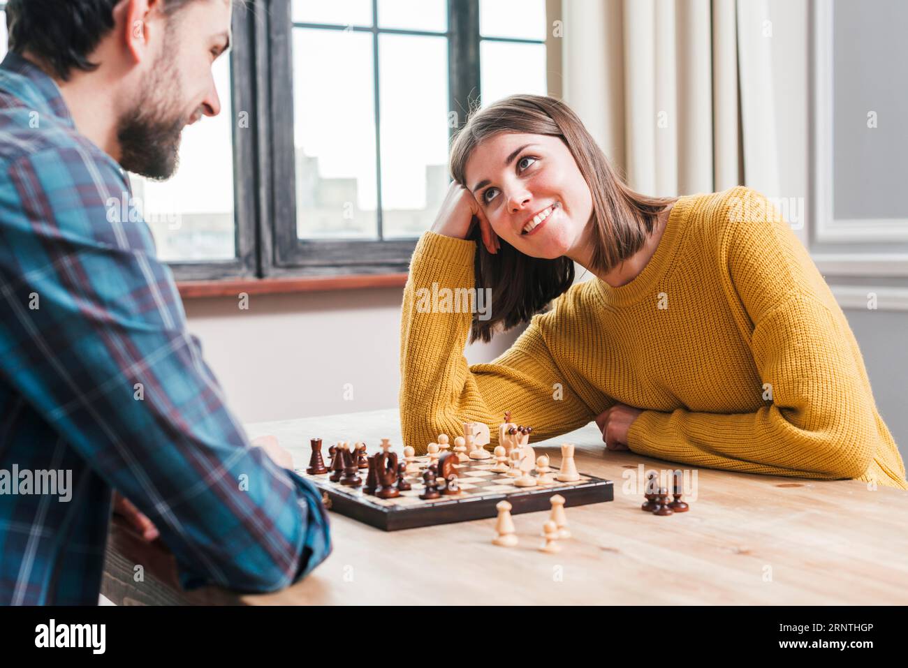 Joven pareja sentada juntos jugando a casa de ajedrez Foto de stock