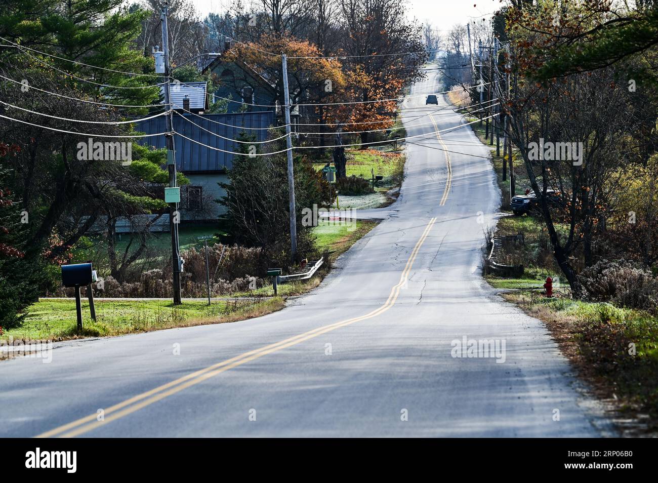 Un coche sube por una carretera ondulada, subiendo una colina en Crosstown Road en Berlín, Vermont, Nueva Inglaterra, EE.UU. Foto de stock