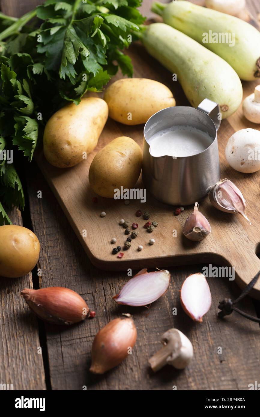 ingredientes para la sopa en una mesa de madera - patatas, crema, calabacín, cebolla, apio Foto de stock