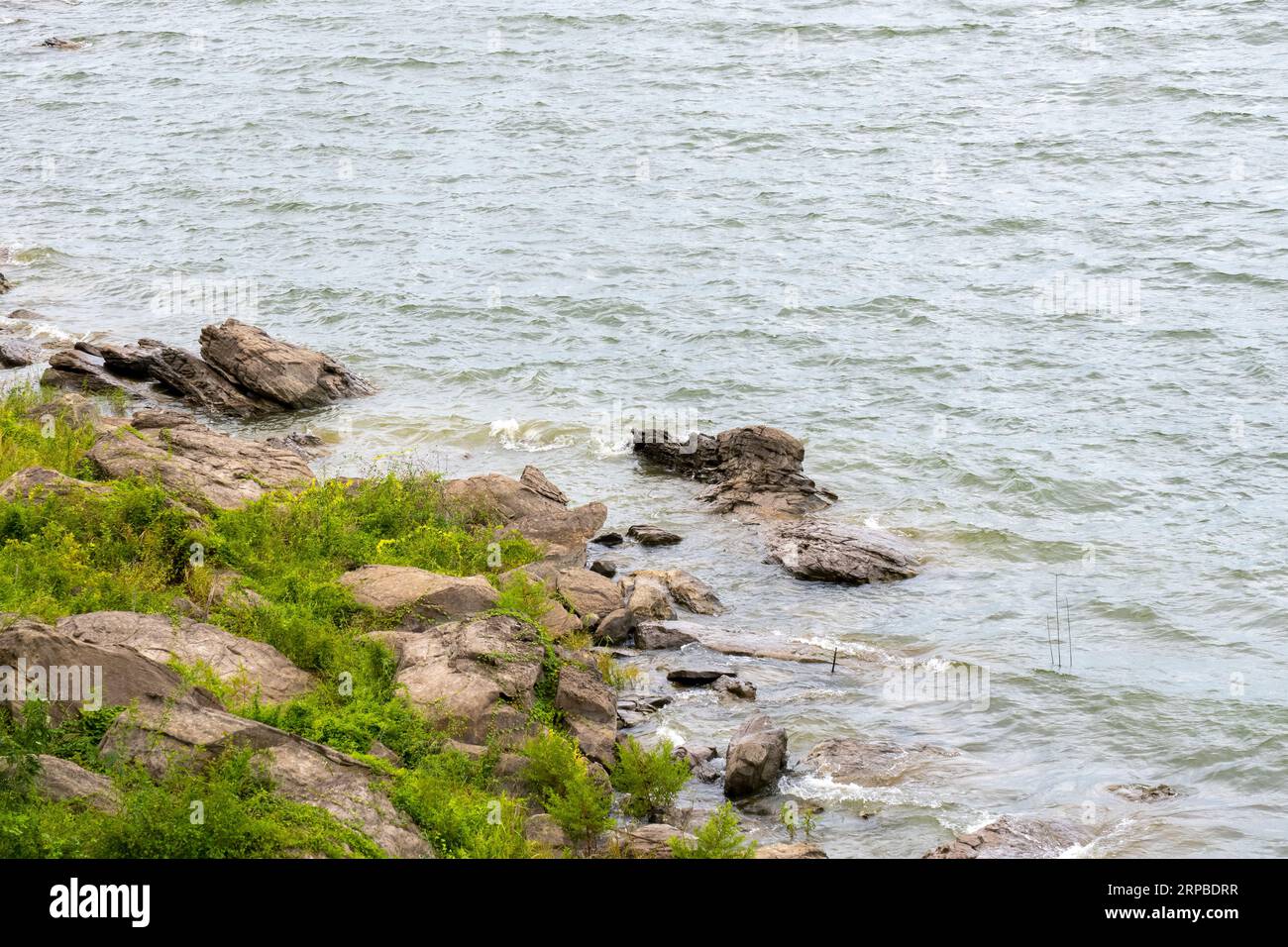 Hay una roca en la playa y el agua de verano es tranquila Foto de stock