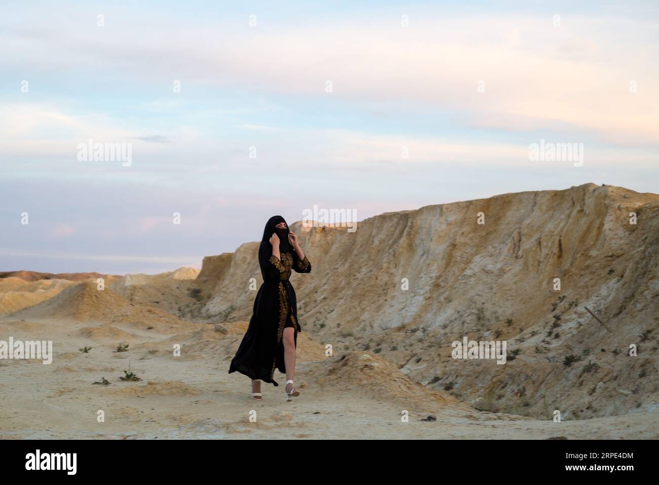 La ropa nacional negra de la mujer del Islam corre a través del desierto del peligro. Mujer perdida en la naturaleza Foto de stock