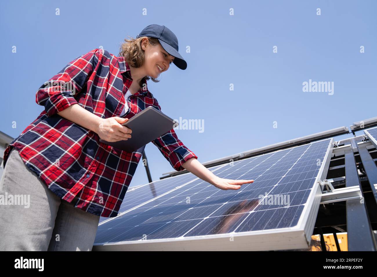 Mujer con la tableta digital en un fondo de la estación de energía solar móvil.. Foto de stock