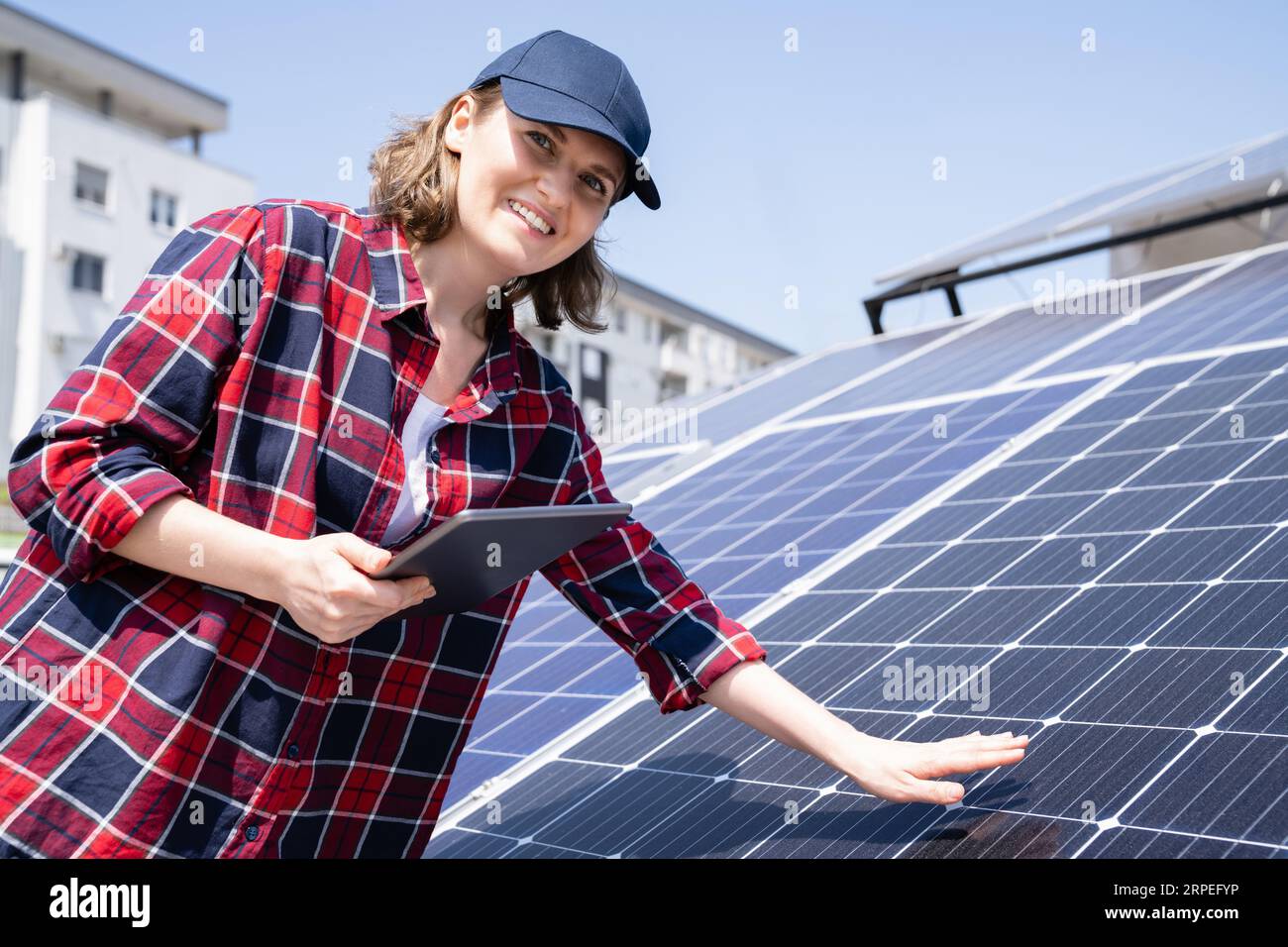 Mujer con la tableta digital en un fondo de la estación de energía solar móvil.. Foto de stock