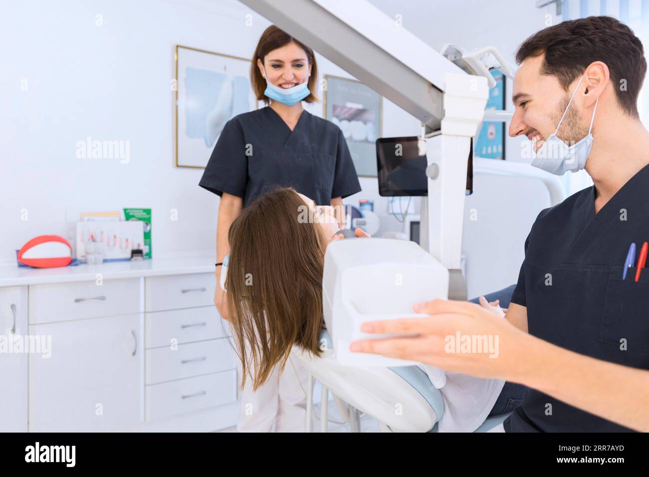 Dentista masculino que escanea los dientes del paciente femenino con la máquina de rayos X. Foto de stock