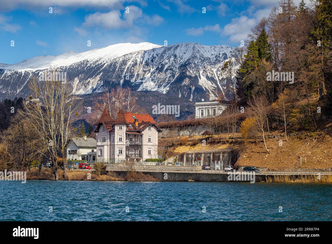 Bled, Eslovenia - Precioso hotel en el lago Bled con los Alpes Julianos en el fondo en un soleado día de invierno. Cielo azul y nubes Foto de stock