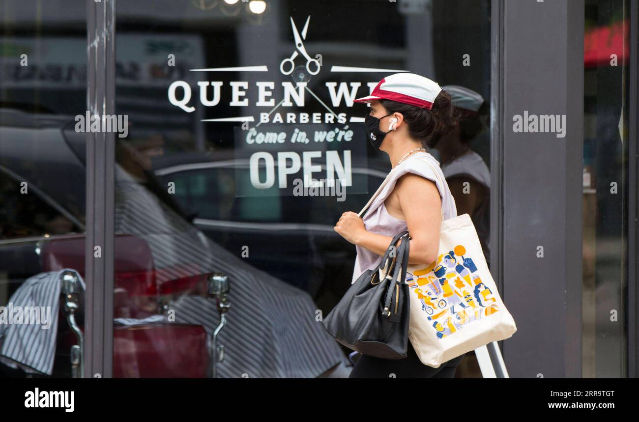 210630 -- TORONTO, 30 de junio de 2021 -- Una mujer pasa frente a una peluquería con un cartel ABIERTO en Toronto, Ontario, Canadá, el 30 de junio de 2021. La provincia canadiense de Ontario permitió que la mayoría de las regiones reabrieran más negocios el miércoles, ya que avanzaron al paso dos del plan de reapertura de la provincia, incluyendo peluquerías, salones de uñas y tiendas en centros comerciales. Foto por /Xinhua CANADA-ONTARIO-COVID-19-REOPENING-STEP TWO ZouxZheng PUBLICATIONxNOTxINxCHN Foto de stock