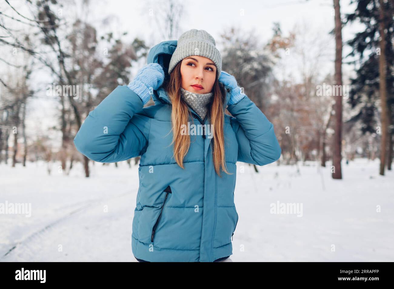 Retrato de la mujer joven que camina en el parque nevado del invierno que  lleva la chaqueta azul abajo del abrigo. Ropa abrigada para el clima frío  Fotografía de stock - Alamy