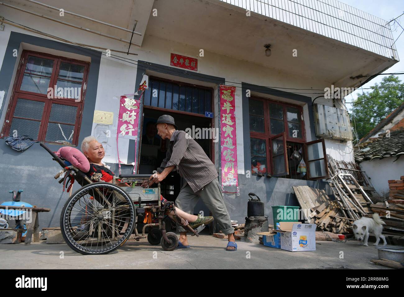 210908 -- NANCHANG, 8 de septiembre de 2021 -- Luo Anmin lleva a su esposa al patio para bañarse un poco de sol en la aldea Xuluo del condado de Nanchang, provincia de Jiangxi, al este de China, 5 de septiembre de 2021. Luo Anmin tiene 76 años. En 2008, su esposa Wan Zhaolian sufrió de cáncer cerebral y desafortunadamente perdió el conocimiento, pero Luo nunca se rindió. Habló con su esposa y le dio masajes todos los días, con la esperanza de que pueda estar mejor algún día. Después de tres años de cuidado amoroso, ocurrió el milagro. En 2011, Wan Zhaolian recuperó la conciencia, lo que le dio a Luo más esperanza, aunque todavía no podía hablar y caminar. Luo dijo h Foto de stock