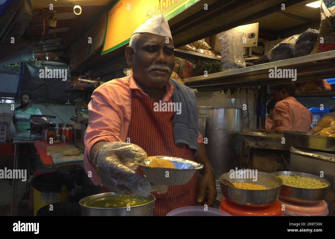 Un vendedor prepara Vada pav, un plato vegetariano de comida rápida, en un puesto de comida en el mercado de alimentos en la playa Chowpatty en Mumbai, India Foto de stock