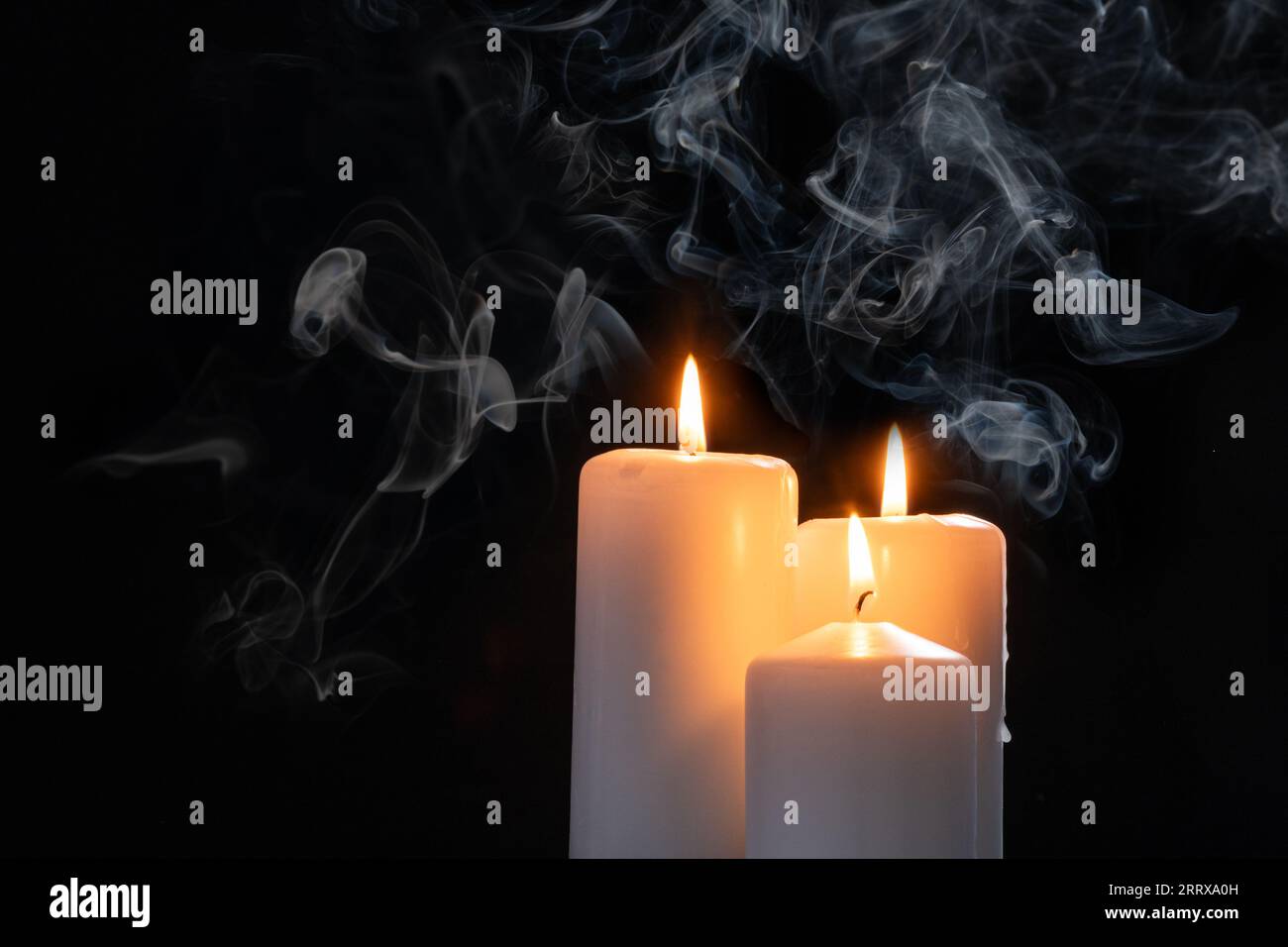 Tres velas blancas dispuestas sobre una tela blanca fotos de