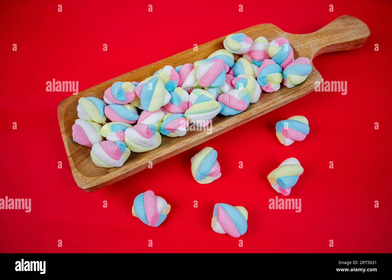caramelo de malvavisco en plato de madera sobre fondo rojo Foto de stock