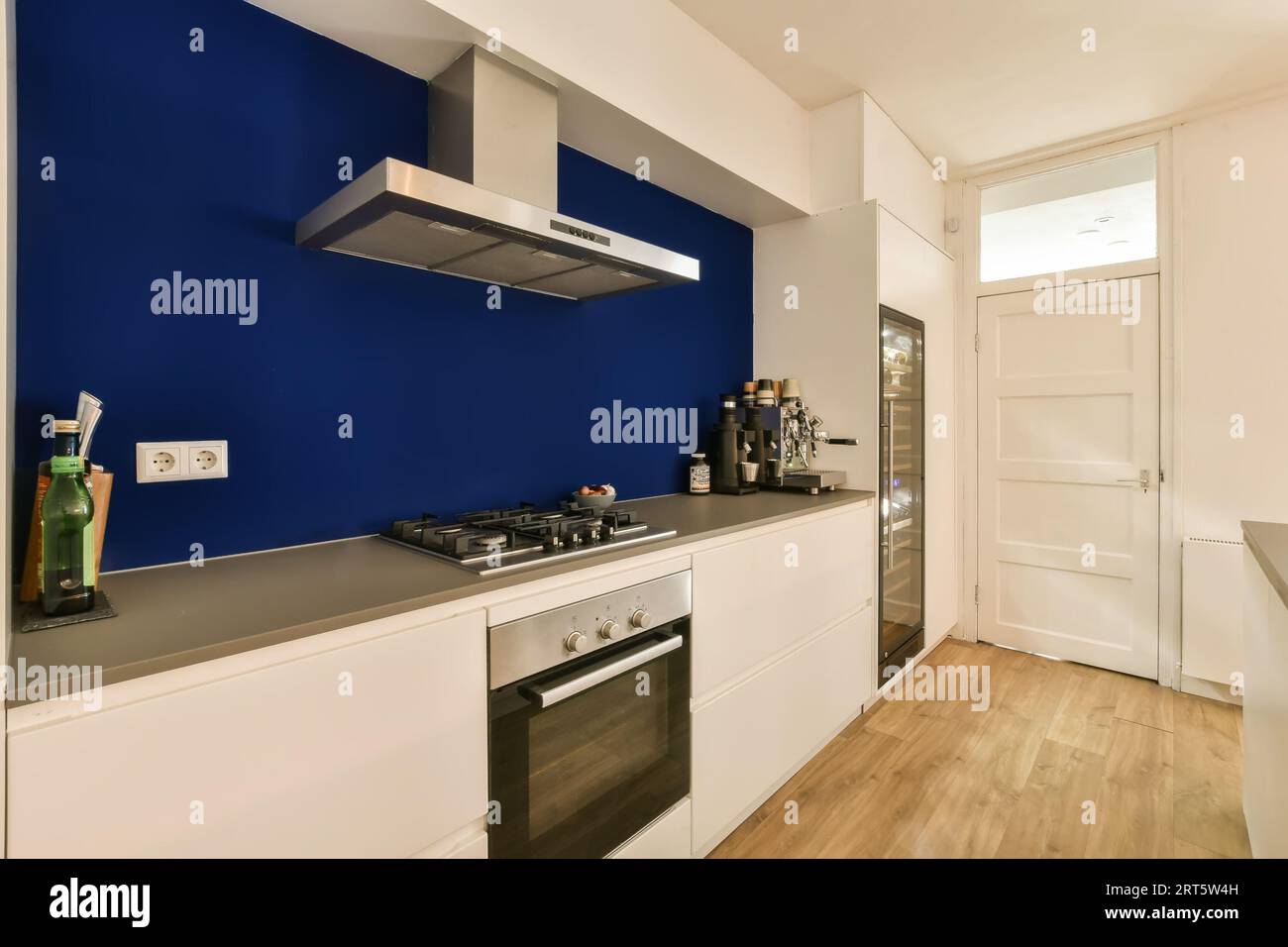 una cocina con paredes azules y armarios blancos en la pared hay un  televisor de pantalla plana montado encima de ella Fotografía de stock -  Alamy