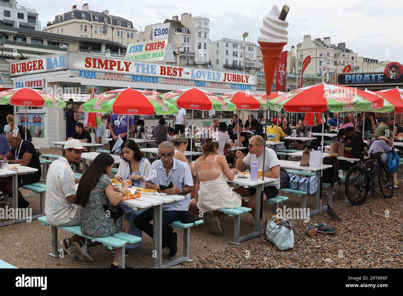 Grupos de personas comiendo comida en un restaurante de pescado y patatas fritas en el paseo marítimo de Brighton Foto de stock