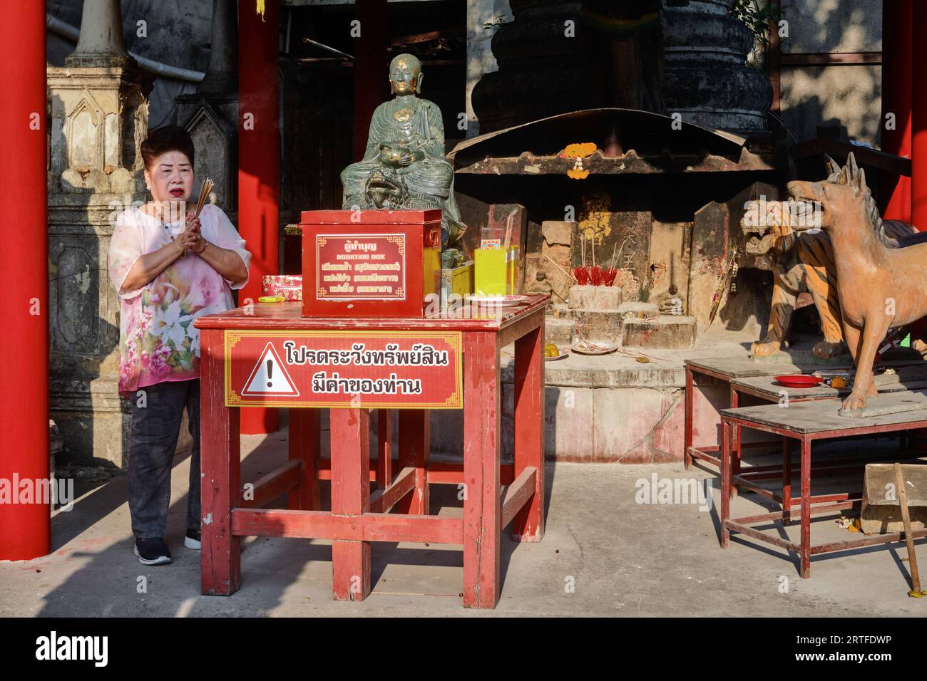 Una mujer orando en una capilla lateral de Wat Mangkon Kamalawat en Chinatown, en Bangkok, Tailandia, un Templo Taoísta mayormente visitado por Thai-Chinese Foto de stock