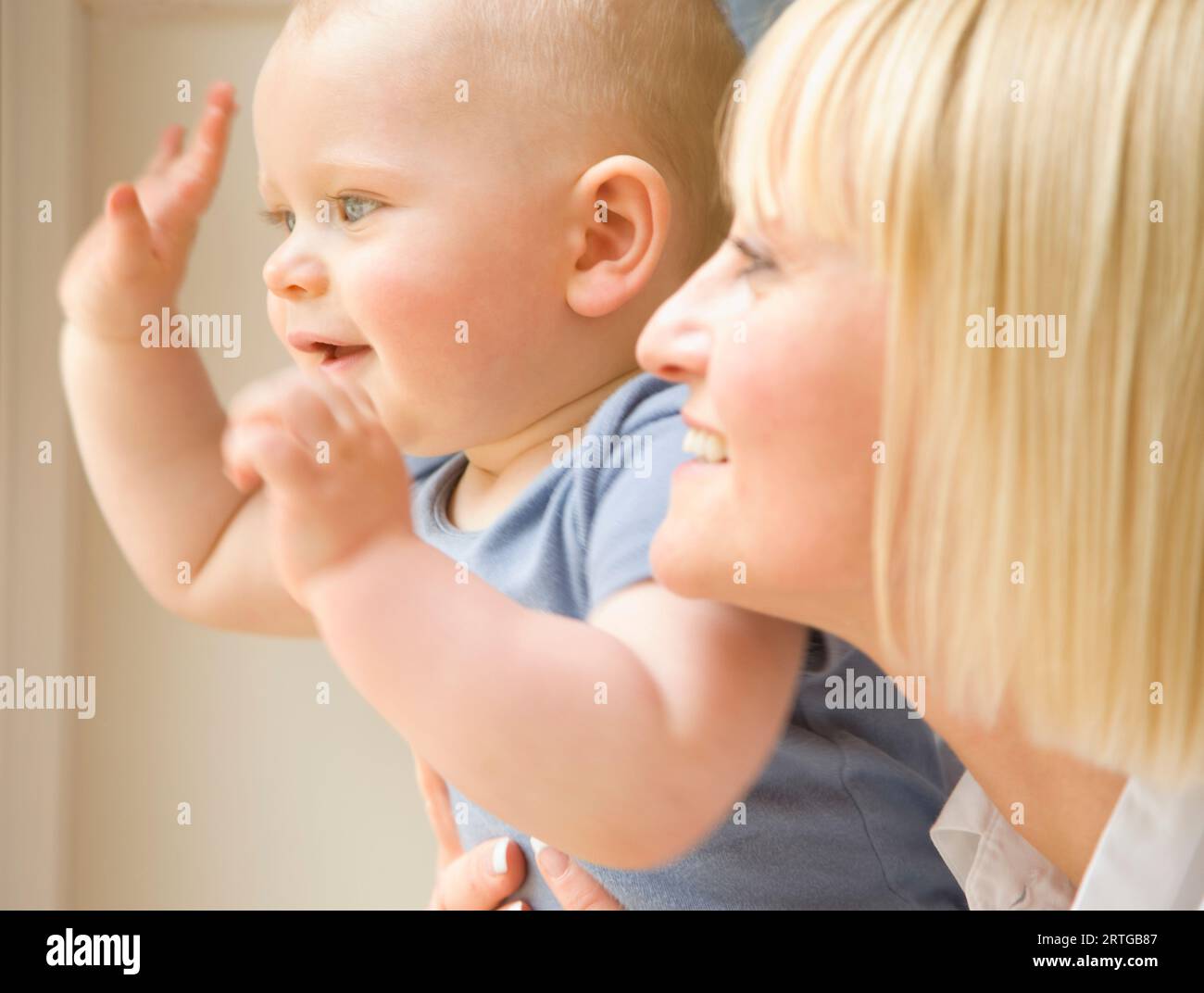 Cerca de un bebé agitando los brazos con su madre sosteniendo él Foto de stock